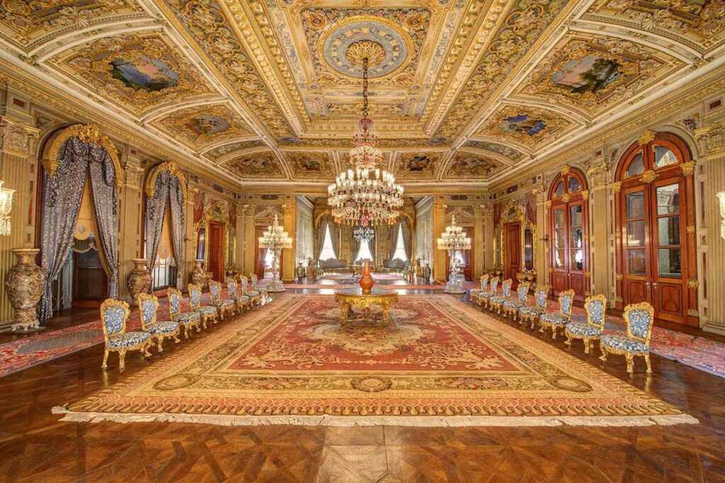 Ornate interior of Yildiz Palace in Istanbul, featuring golden ceilings, luxurious chandeliers, intricate carpets, and elegant seating.