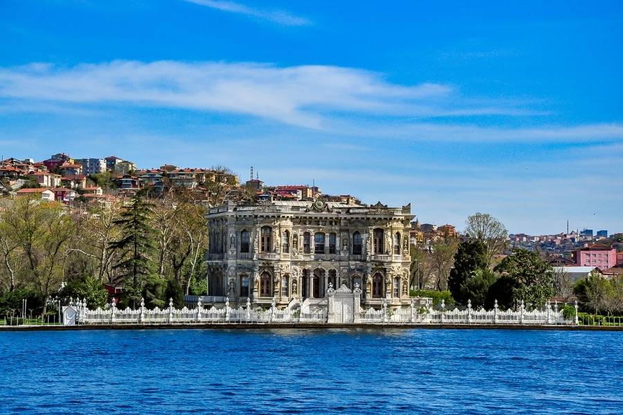 Küçüksu Pavilion on the Bosphorus in Istanbul, featuring intricate architecture, lush surroundings, and a serene waterfront view.